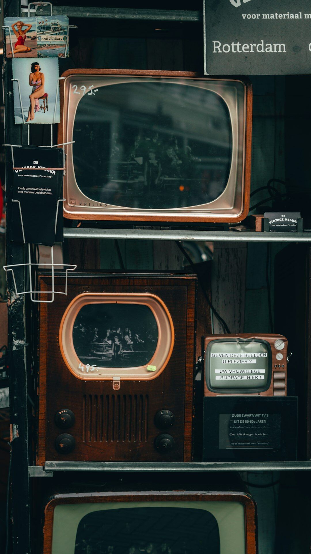 Stack of vintage television sets displaying old commercials